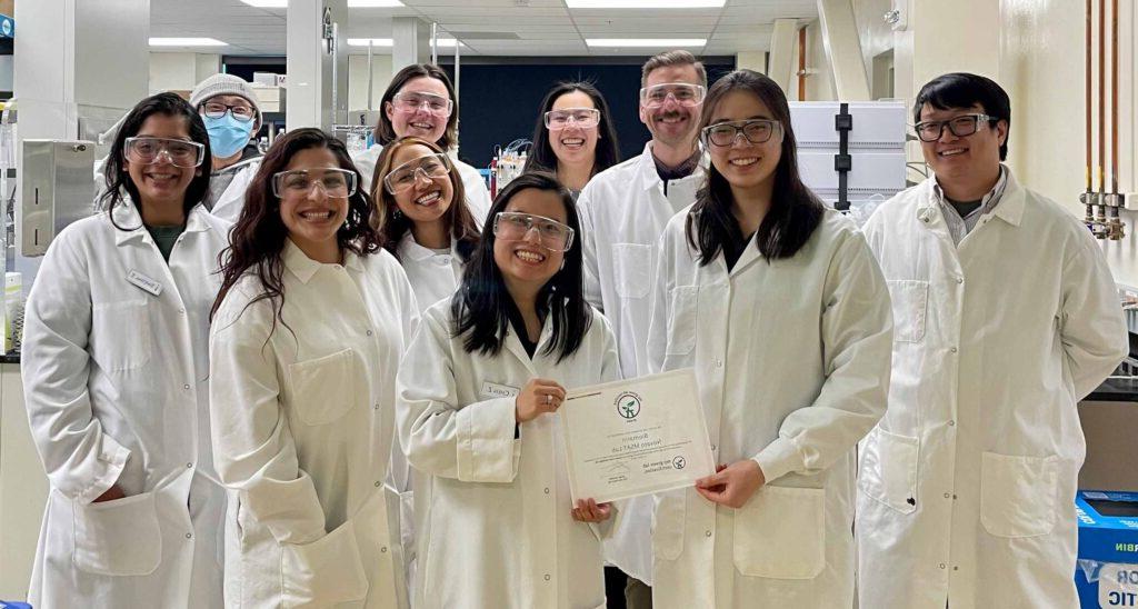 澳门正规博彩十大排行平台的制造科学和技术团队在实验室里拿着我的绿色实验室认证